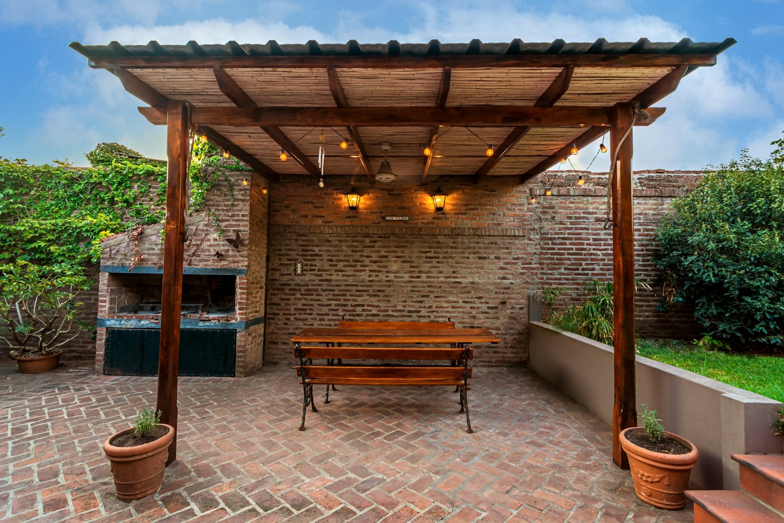 Wooden pergola over a brick patio with a bench and grill (photo: Rafael Hoyos Weht / Unsplash)