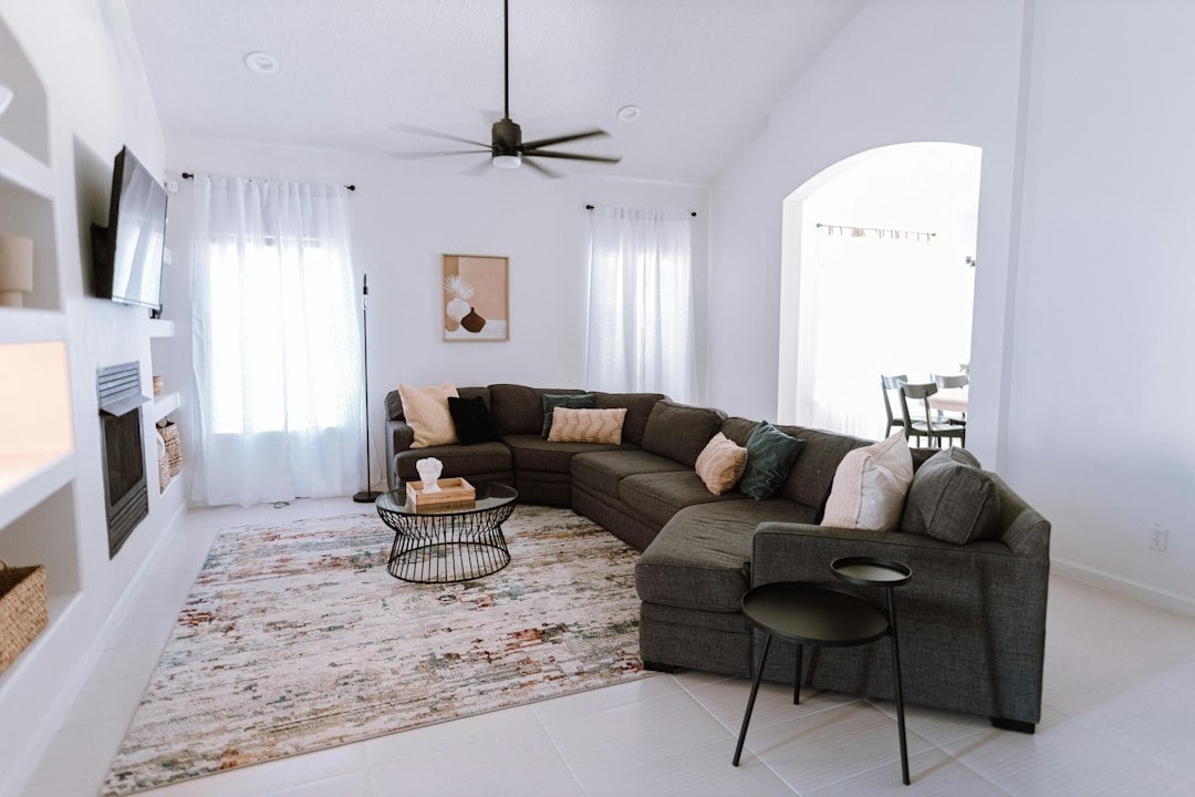 Minimalist holiday home living area with a dark grey sectional and patterned rug