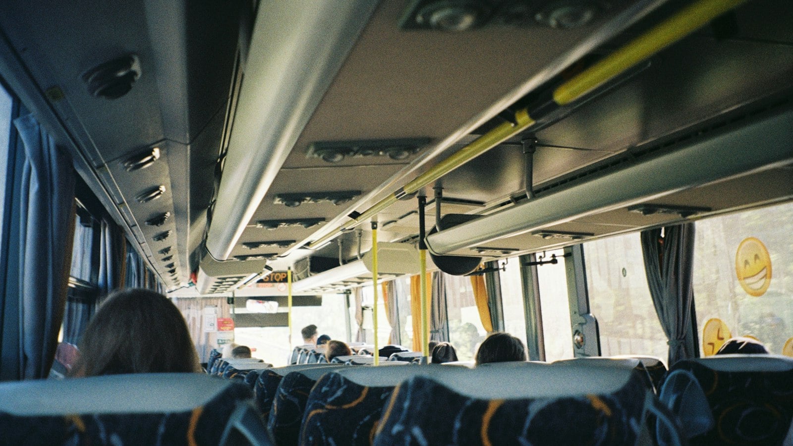 The aisle of a coach looking forward, with open overhead luggage racks along both sides