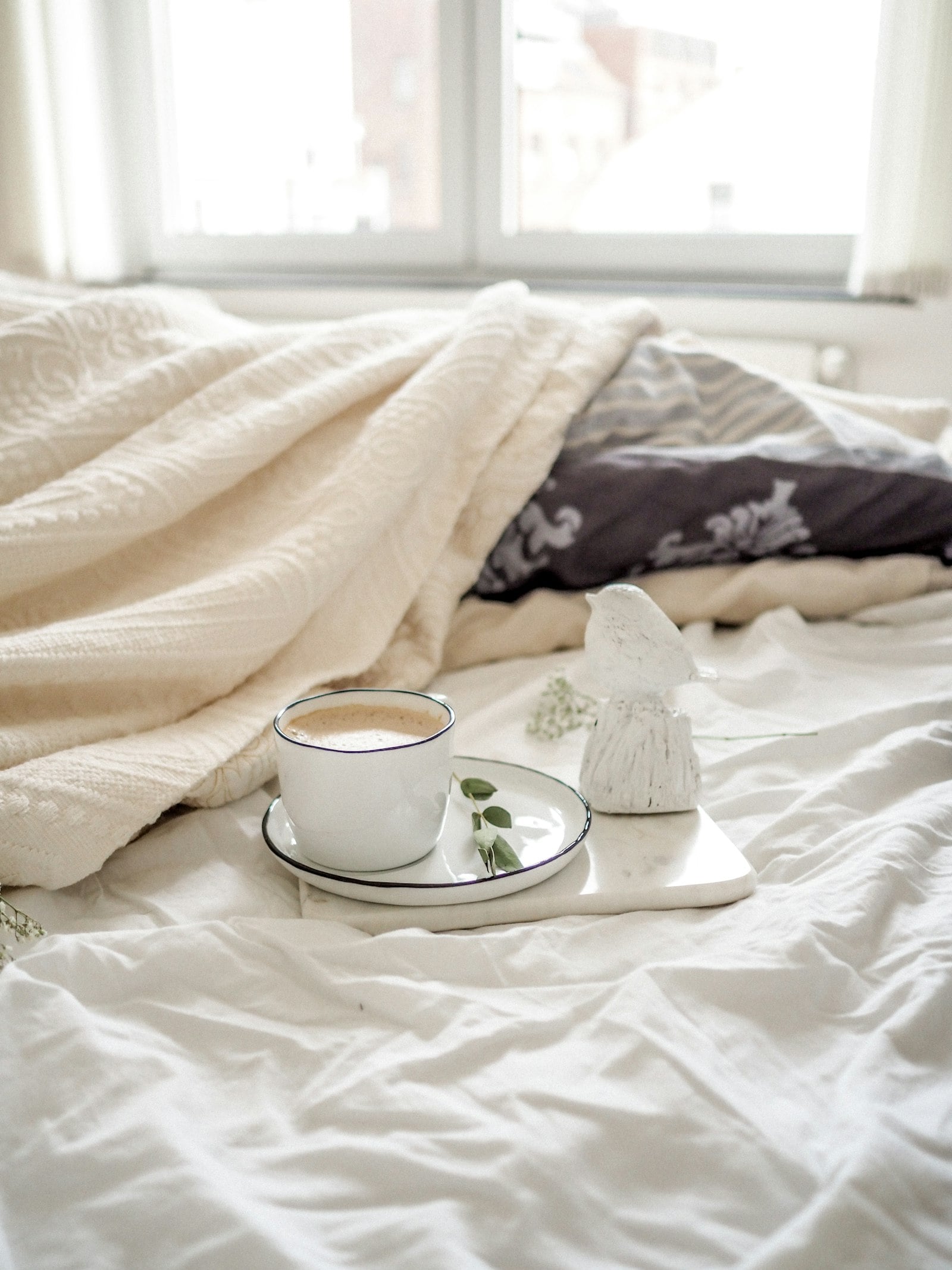 Cup of coffee on a tray on a cream blanket (photo: Jen P. / Unsplash)