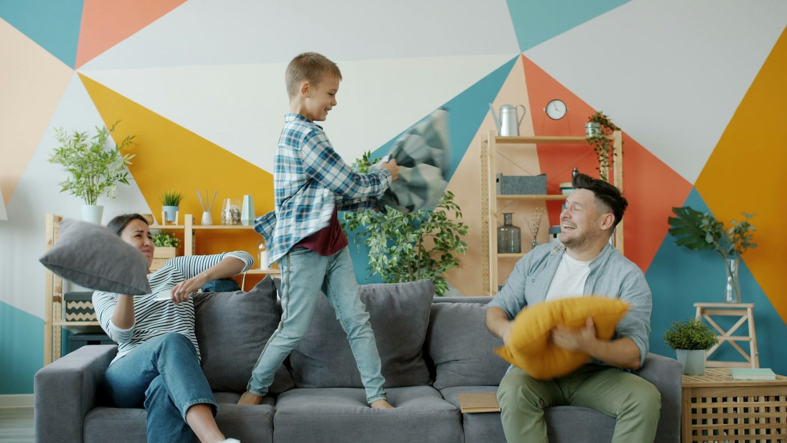 Family having a pillow fight on a grey sofa at home (photo: Vitaly Gariev / Unsplash)