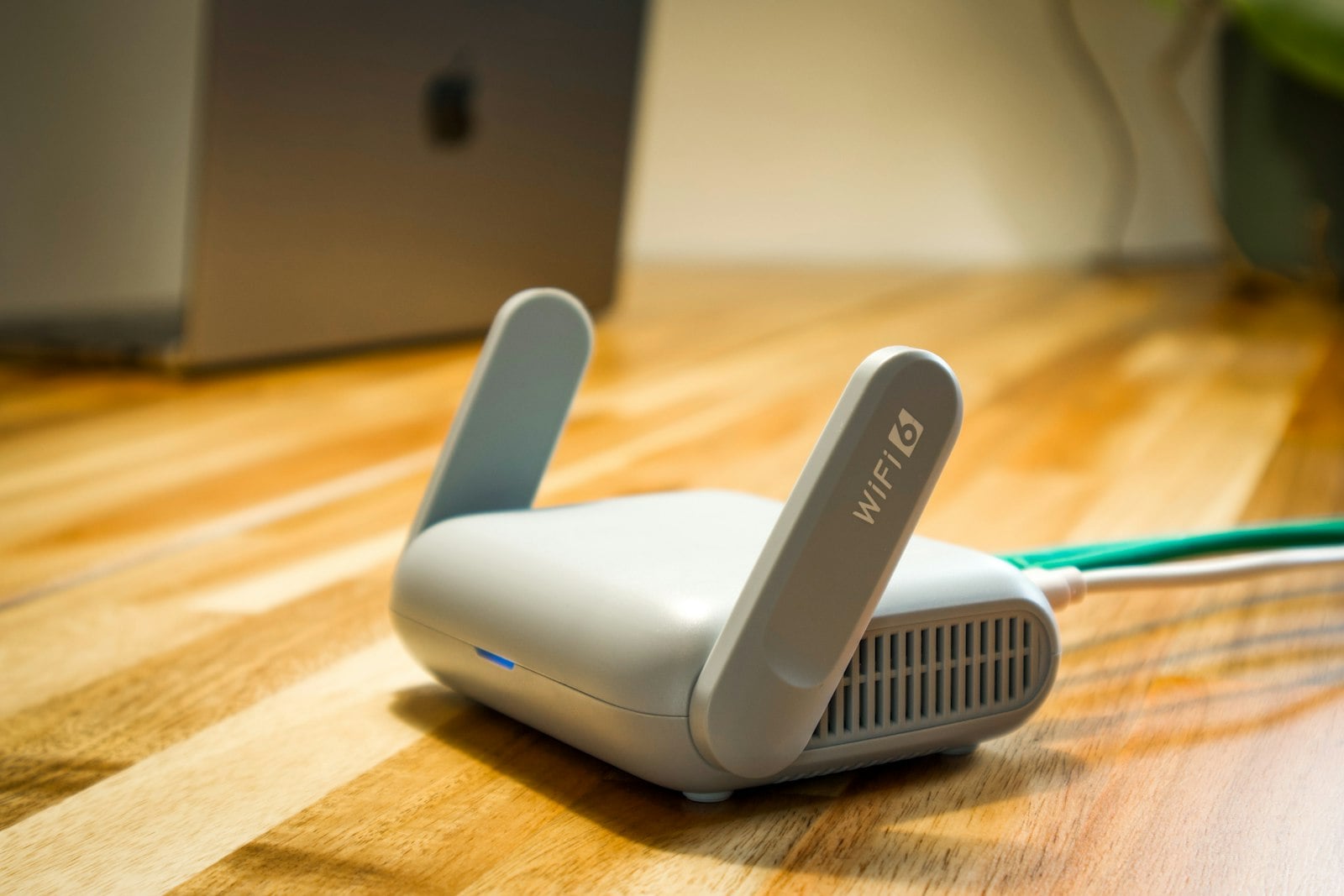 Small white Wi-Fi router on a wooden desk (photo: User_Pascal / Unsplash)