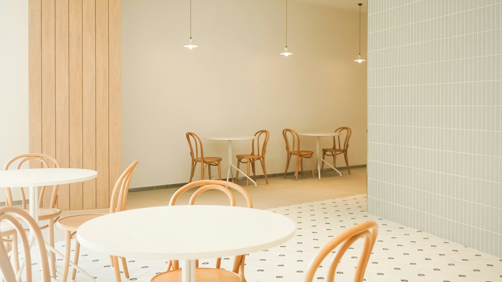 A minimal café with round white tables, bentwood chairs and a patterned tile floor (photo: JIRAN FAMILY / Unsplash)