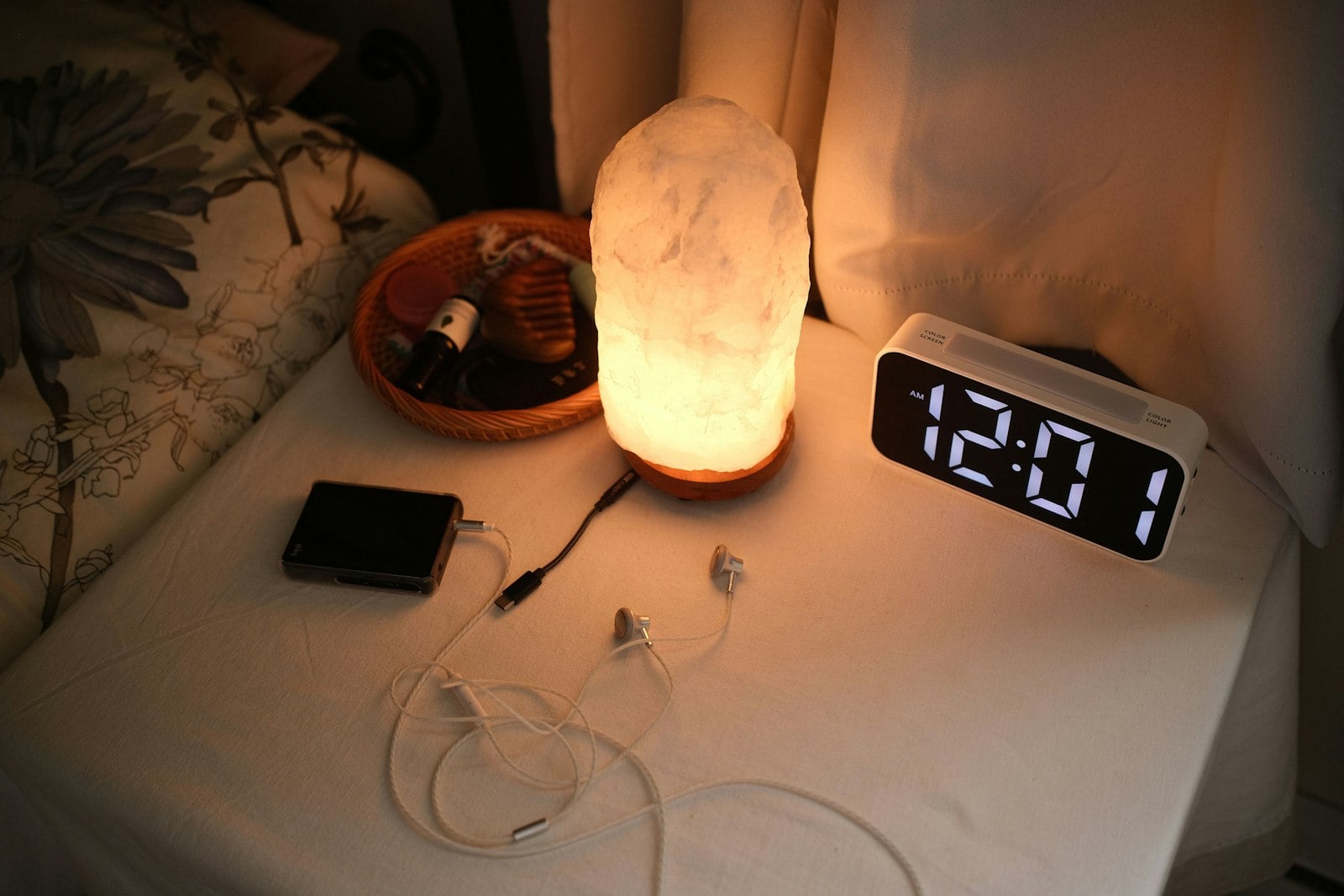 Bedside table with a digital alarm clock and a salt lamp at night (photo: Allen Y / Unsplash)