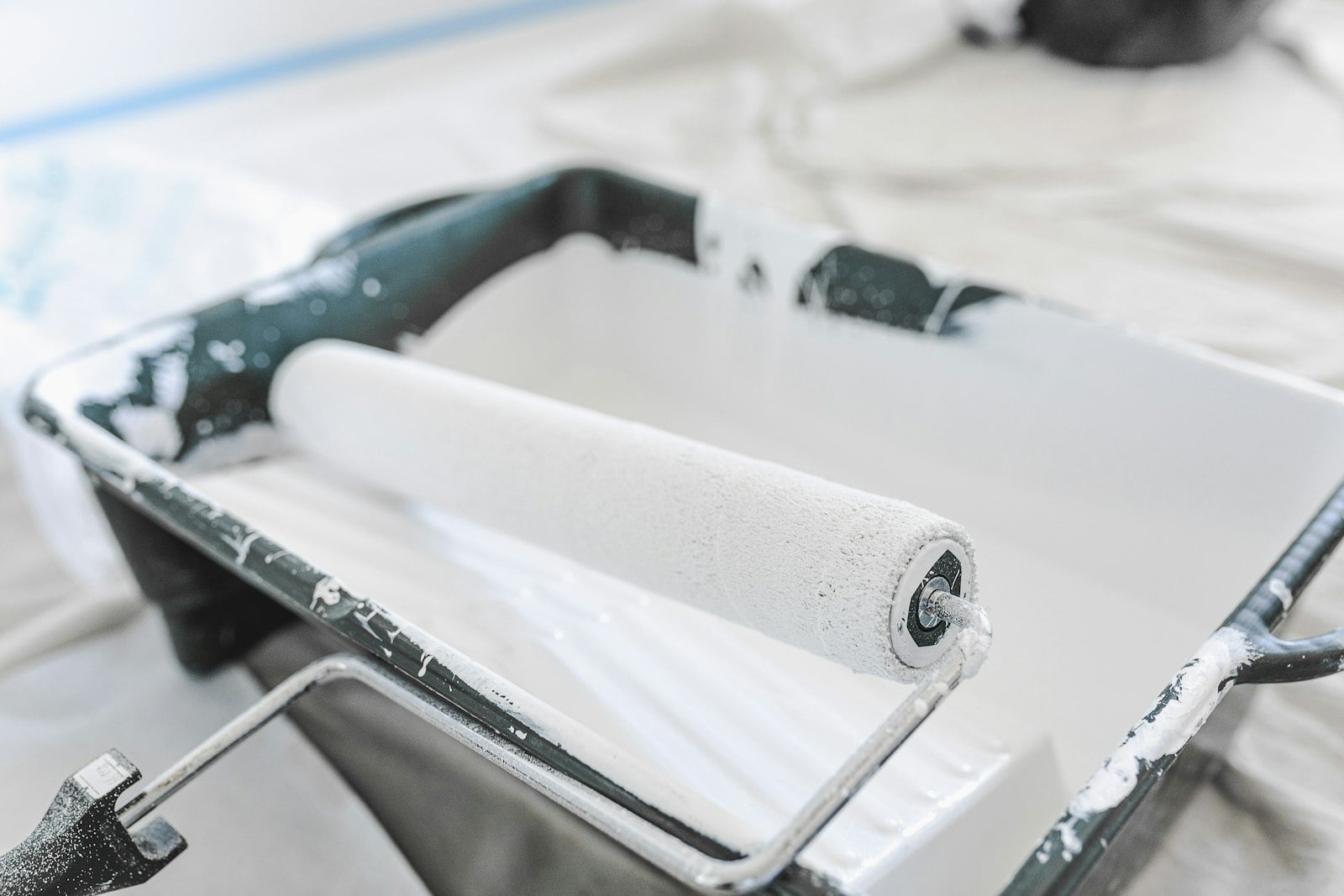 Paint roller resting in a tray of white paint (photo: Callum Hill / Unsplash)