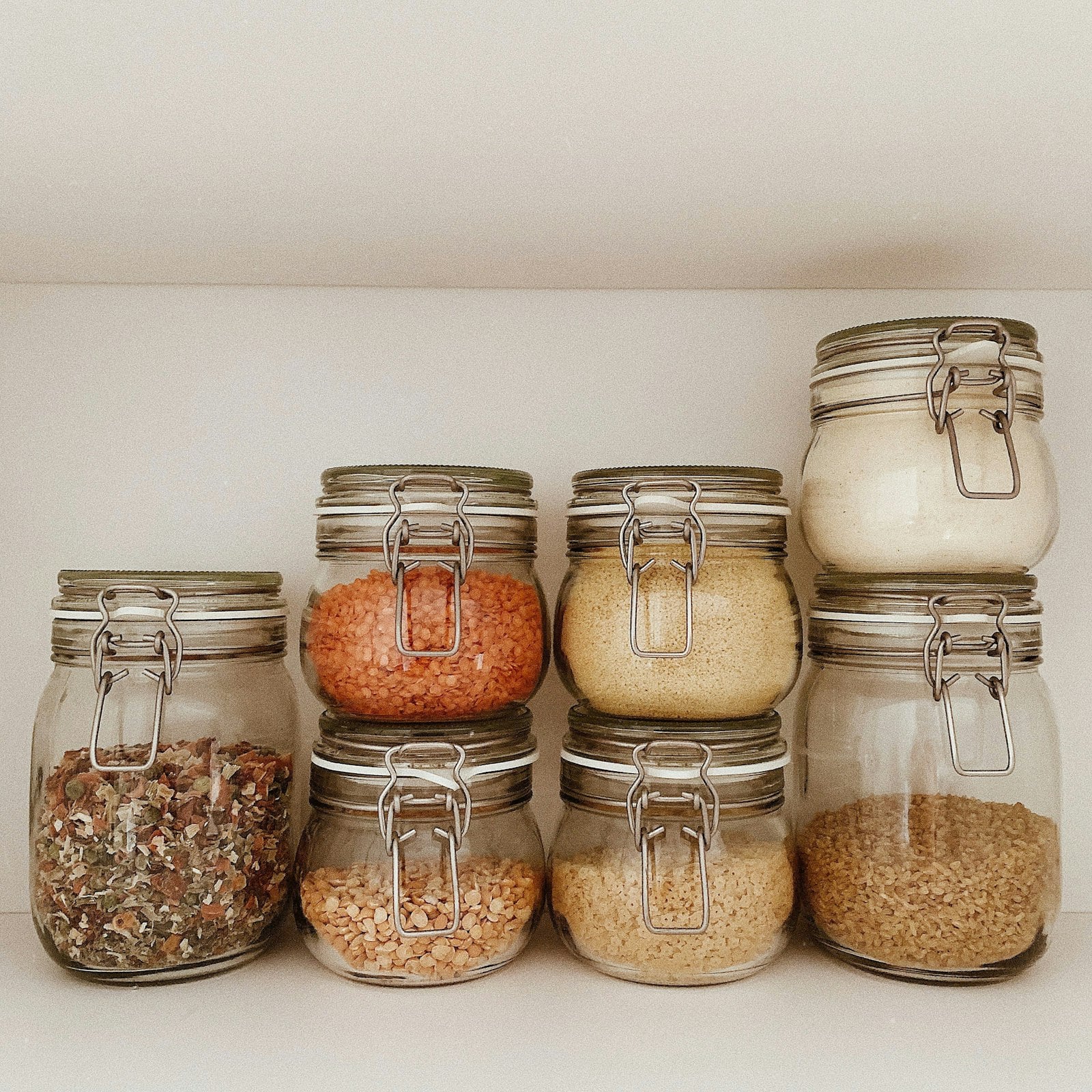 Stacked clip-top jars of lentils and grains on a pantry shelf (photo: Nadia Pimenova / Unsplash)
