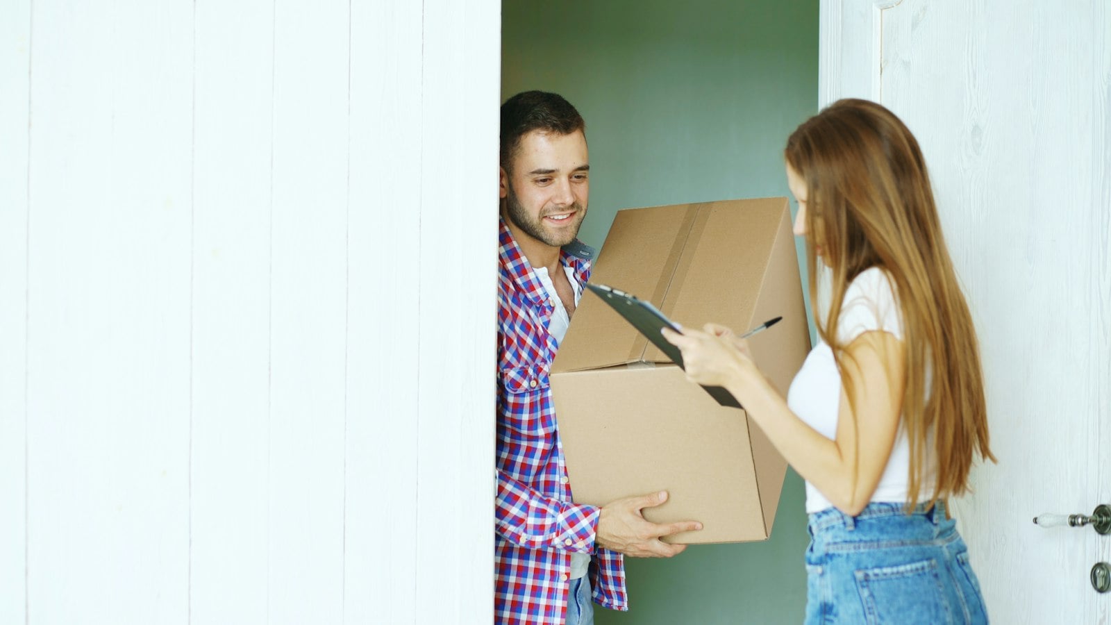 Courier handing a cardboard parcel to a woman at her front door (photo: Vitaly Gariev / Unsplash)