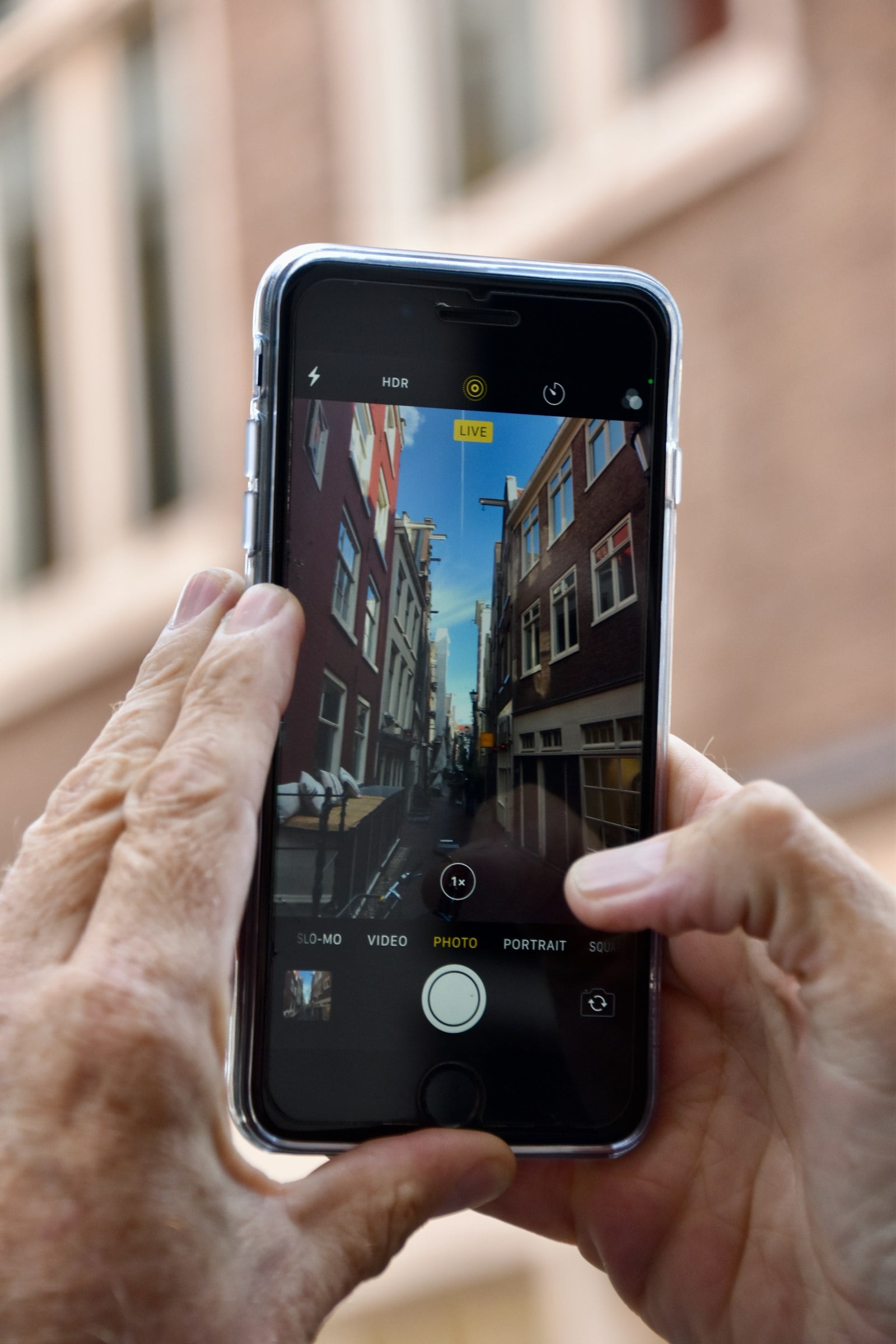 Hands holding a smartphone up to photograph a city street (photo: Samuel Isaacs / Unsplash)