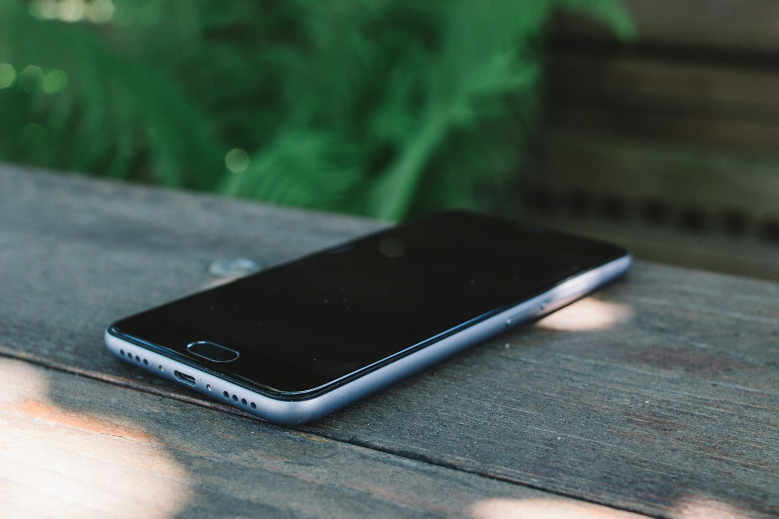 Smartphone lying face down on a weathered outdoor table (photo: Olga Nayda / Unsplash)