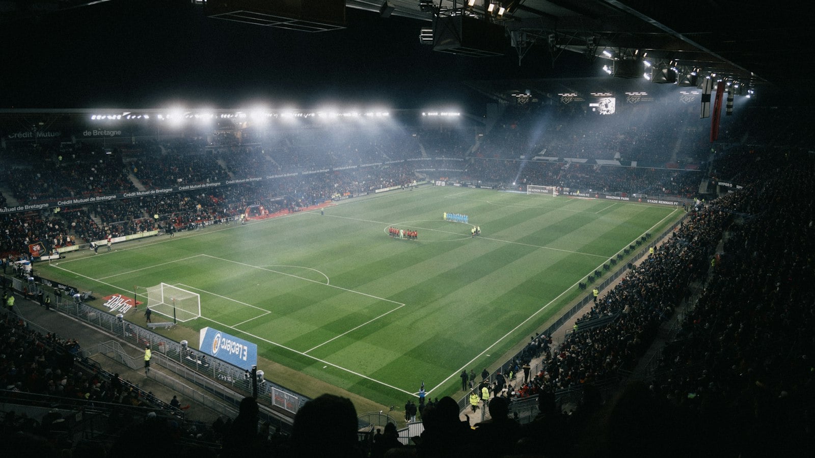 A floodlit football stadium at night (photo: Howard Bouchevereau / Unsplash)