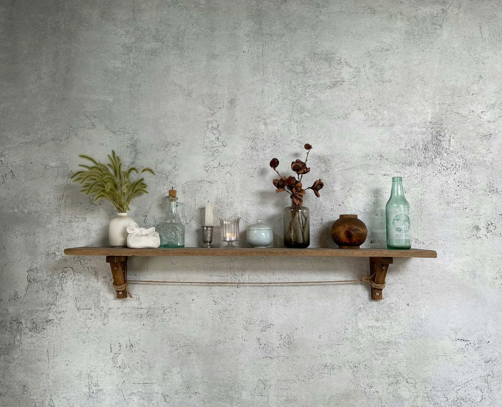 Wooden wall shelf styled with old glass bottles and small vases (photo: cHoLoNg cHoI / Unsplash)