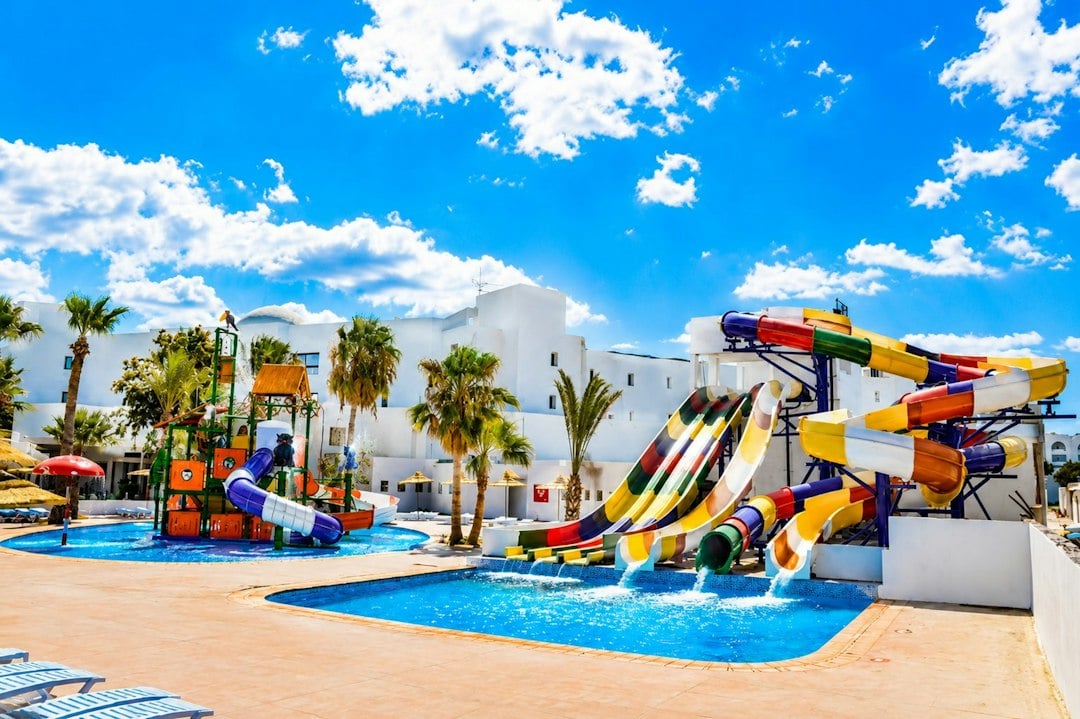 Bright multicolored water slides pour into a shallow pool at a whitewashed holiday resort
